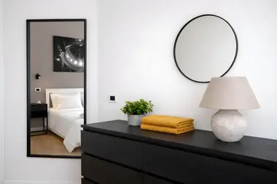 a black dresser with a lamp and a mirror at Sunny Monteverde Apartment - Near Trastevere by RHR in Rome