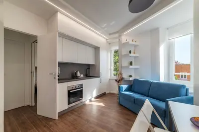 a living room with a blue couch and a kitchen at GuestHost - Monteverde Classy Apartment in Rome
