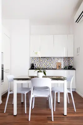 a white kitchen with a white dining table and white chairs at Trastevere Station House in Rome