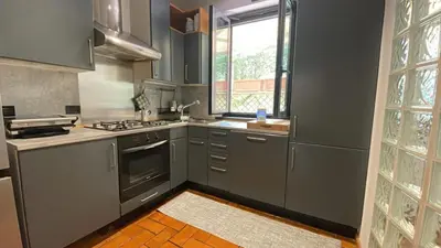 a kitchen with gray cabinets and a stove and a window at Vatican Luxury Apt with Garden in Rome