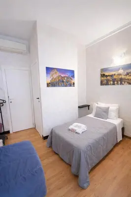a bedroom with a bed with blue walls and a window at Vatican Rooms Haven in Rome