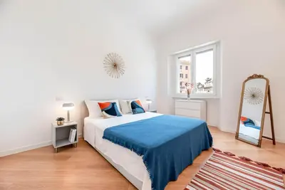 a white bedroom with a large bed and a mirror at Appartamento Basilica di San Giovanni in Laterano in Rome