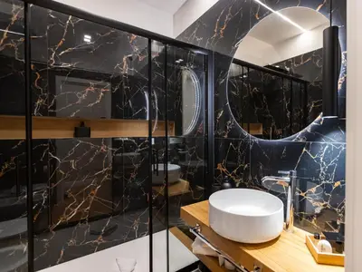 a bathroom with a black and gold marble wall at Regola Luxury Relais in Rome