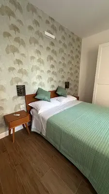 a bedroom with a bed with a green blanket and a table at A casa di Edo in Rome
