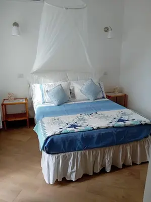 a bedroom with a bed with blue sheets and pillows at Le Buganville in Rome