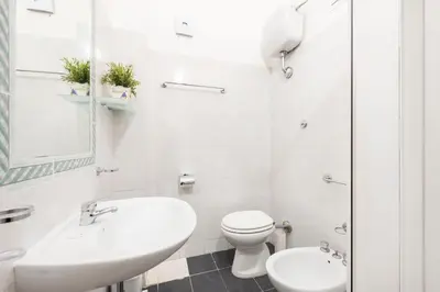 a white bathroom with a toilet and a sink at Hotel Infinito - Gruppo BLAM HOTELS in Rome