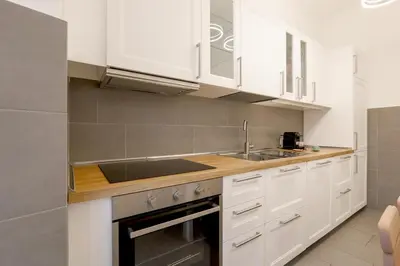 a kitchen with white cabinets and a sink at Piramide Deluxe Apartment in Rome
