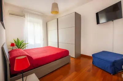 a bedroom with a red bed and a flat screen tv at Clodia Vatican House in Rome
