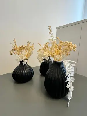 three black vases with flowers in them on a table at Vatican R(h)ome in Rome