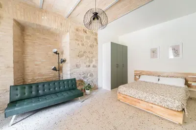 a bedroom with a green couch and a stone wall at FAMM - Cozy flat in Trastevere in Rome