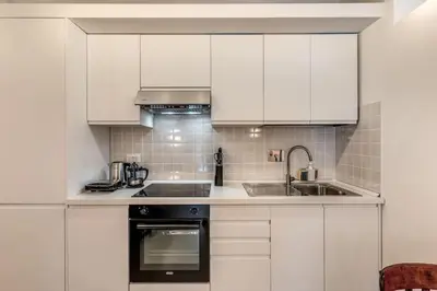 a kitchen with white cabinets and a sink at Trastevere Vicolo del Leopardo suite in Rome