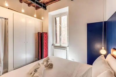 a bedroom with a white bed and a window at Trastevere Vicolo del Leopardo suite in Rome