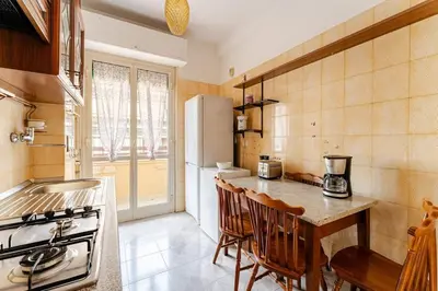 a kitchen with a counter with chairs and a refrigerator at Green Holiday Penthouse in Rome