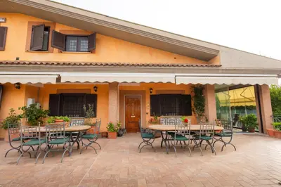 a patio with tables and chairs in front of a building at Villa Aureliana with pool near San Peter in Rome