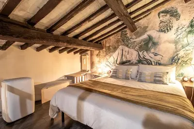 a bedroom with a large bed with a painting on the wall at Suite Benedetta - Trastevere Luxury in Rome