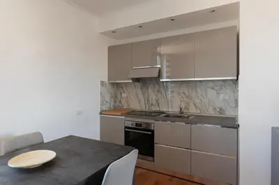 a kitchen with white cabinets and a table with a sink at GuestHost - MM San Giovanni Apartment in Rome