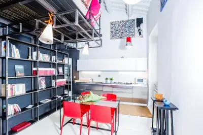 a dining room with red chairs and a table and bookshelves at Trastevere Design Loft - My Extra Home in Rome