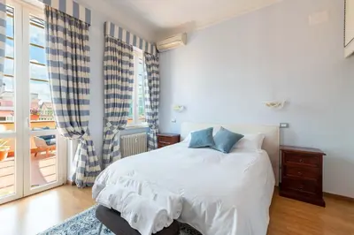 a bedroom with a white bed and a large window at Coppede' Penthouse in Rome