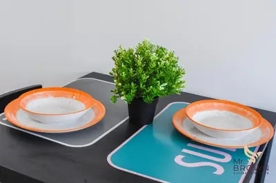 two orange and white plates and a potted plant on a table at MrBrown - Pincherle Room in Rome