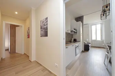 a kitchen with white cabinets and a wooden floor at Prestigious Re di Roma Apartment in Rome