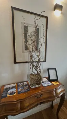a table with a glass vase with branches in it at QUIRINALE 56 suite in Rome