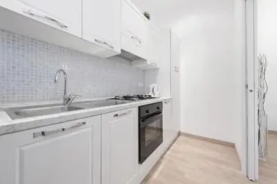 a white kitchen with a sink and a stove at White Flat Colosseo in Rome