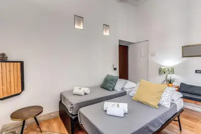 a living room with two beds and a table at Trastevere at Piazza Giuditta Arcuati suite in Rome