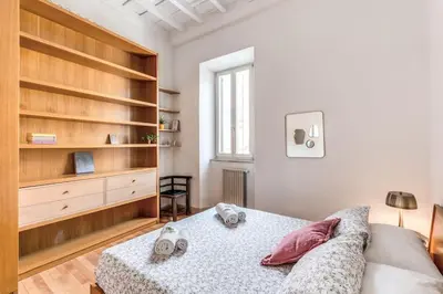 a white bedroom with a bed and wooden shelves at Trastevere at Piazza Giuditta Arcuati suite in Rome