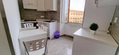 a small kitchen with white cabinets and a window at Rome Aparts - Deluxe Apartment with 3 bedrooms at St Peter square in Rome
