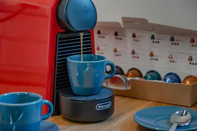 a coffee maker pouring coffee into two blue cups at Glorioso Apartment Trastevere in Rome