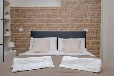 a bed with two pillows and a brick wall at Glorioso Apartment Trastevere in Rome
