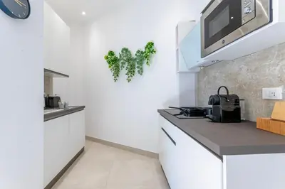 a kitchen with white cabinets and a tv on the wall at Roma apartment near to Colosseum Re-House in Rome