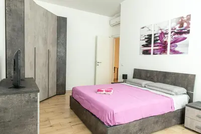 a bedroom with a pink bed and a tv at Rea house Colli Albani - B&Brother's rome in Rome