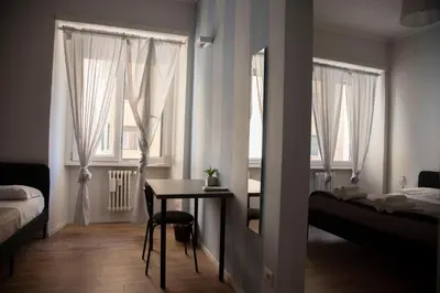 a room with a table and a bed and windows at PiazzaBolognaStay in Rome