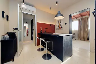 a kitchen with a black counter with stools at 100m dal Vaticano Oasi Luxury 2 Terraces in Rome
