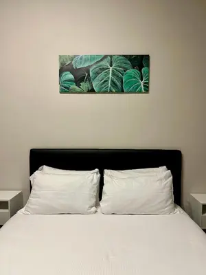 a bedroom with a bed with white sheets and green leaves at D Guest House in Rome