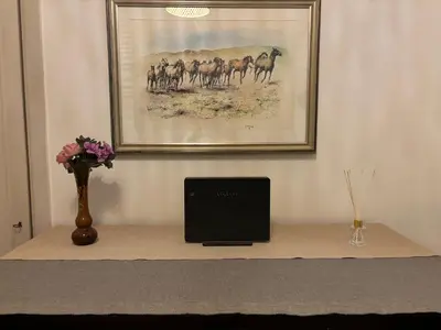 a laptop computer sitting on a table with a vase of flowers at Accogliente Appartamento Roma in Rome