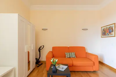an orange couch in a living room with a table at iFlat Bright & Comfy 2-Bedroom Apt near Vatican in Rome