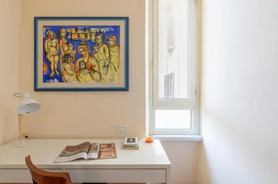 a desk in a room with a painting on the wall at iFlat Bright & Comfy 2-Bedroom Apt near Vatican in Rome