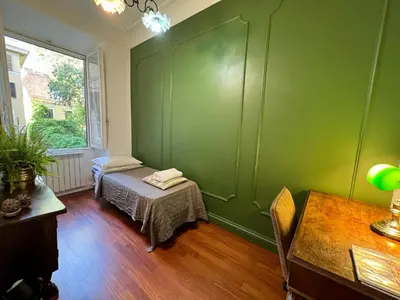 a green room with a bed and a table at House Maximo at Colosseum in Rome