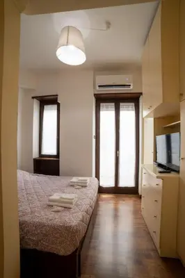 a room with a bed and a kitchen with a television at Richard & Lulù in Rome in Rome
