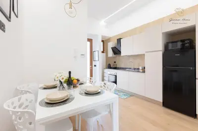 a white kitchen with a white table and a black refrigerator at Gemma House - 100mt to Metro Station, 2 En-Suite bathrooms in Rome