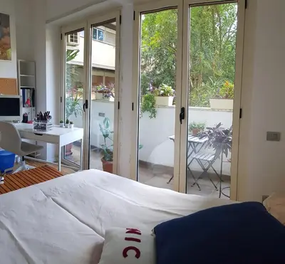 a bedroom with a bed and a desk and sliding glass doors at Parco della Musica House in Rome