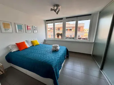 a bedroom with a bed with a blue comforter and two windows at Casa Vivi in Rome