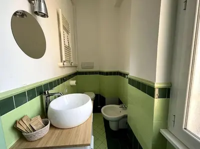 a green and white bathroom with a sink and a toilet at Casa Vivi in Rome