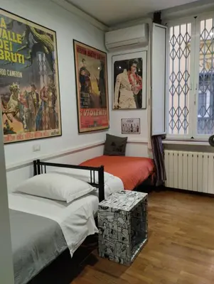 two beds in a room with posters on the walls at Colosseo Vintage Apartment in Rome