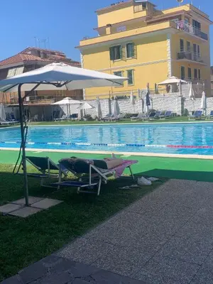 a person laying in chairs under an umbrella next to a pool at Vatican New home in Rome in Rome