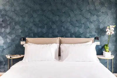 a bed with white pillows and a blue wall at Elysium Suites Colosseo in Rome