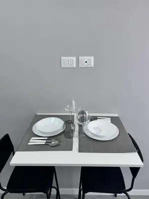 a table with two white plates and wine glasses at Maison Monferrato in Rome
