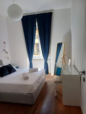 a bedroom with a bed with blue curtains and a mirror at Greta's house in Rome